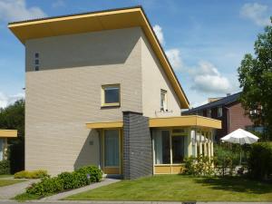 una casa con un giallo e grigio di vakantiehuisgalamadammen met ligplaats boot a Koudum