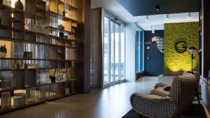 a room with a library with a chair and bookshelves at G Hotel Pescara in Pescara