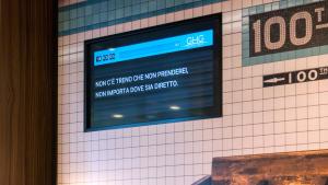 a tv on a wall with a sign on it at G Hotel Pescara in Pescara