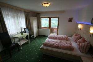 ゲルロスベルクにある"Adamerhof"のベッド、椅子、テーブルが備わるホテルルームです。