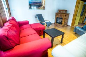 a living room with a red couch and a fireplace at Chalupa Přeslička in Rejvíz