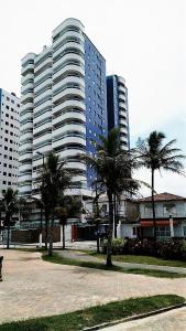 a large building with palm trees in front of it at Apartamento Portal do Sol in Praia Grande