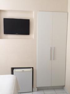 a bedroom with a white cabinet and a flat screen tv at Hotel Porto Grande in Maceió