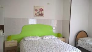 Tiarno di SopraにあるB&B ai Piniの緑のヘッドボード付きのベッド1台(ベッドルーム内)