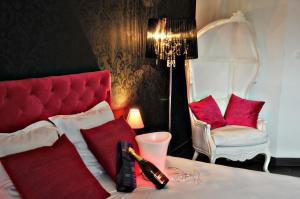 een kamer met een bed met rode kussens en een stoel bij Hôtel Verone - Liège Centre in Luik