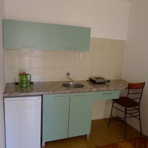 encimera de cocina con fregadero y silla en Apartments Maslina, en Sveti Stefan