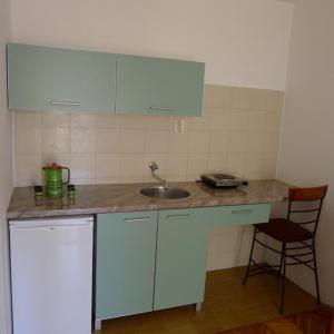 a kitchen counter with a sink and a chair at Apartments Maslina in Sveti Stefan