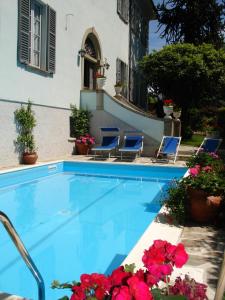 a swimming pool with chairs and flowers in front of a house at Villa Annamaria B&B in Domaso