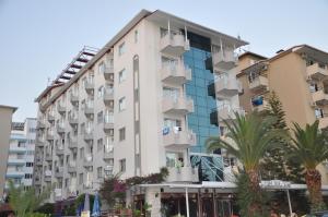 a large white building with palm trees in front of it at Kleopatra Celine Hotel in Alanya