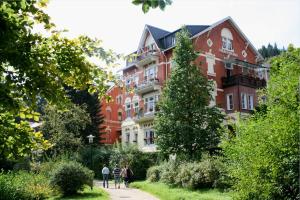 a group of people walking down a path in front of a building at Hotel-Pension SCHLOSS -MIRAMAR in Bad Elster