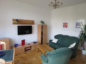 a living room with a green couch and a tv at Hotel-Pension SCHLOSS -MIRAMAR in Bad Elster +3 photos