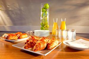 a table with three plates of croissants and wine glasses at Kyriad Direct Saint-Dizier in Saint-Dizier