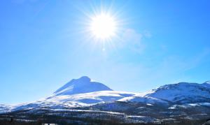 una montaña cubierta de nieve con el sol en el cielo en Lyngseidet Gjestegård, en Lyngseidet