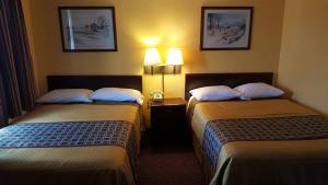 two beds in a hotel room with two lamps at Budget Host Inn Somerset in Somerset