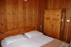 una camera con un letto e una parete in legno di Camping Camplani a Zone