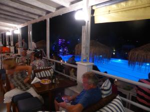 a group of people sitting at a restaurant with a pool at Blue Nest Hotel in Tigaki