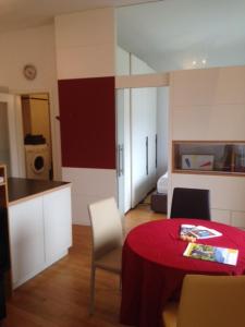 un soggiorno con tavolo rosso e una cucina di Apartment G.Verdi a Bolzano
