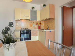 a kitchen with white cabinets and a wooden table at Appartamento Perla in Lido di Pomposa