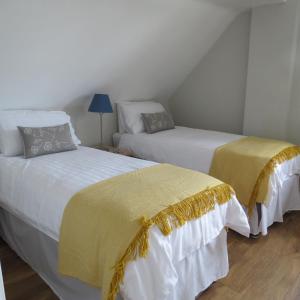 two beds with yellow and white sheets in a room at Maltings Loft in Hepworth