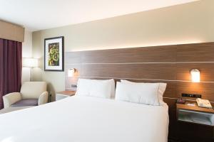 ウォルターボロにあるHoliday Inn Express & Suites Walterboro, an IHG Hotelの大きなベッドと椅子が備わるホテルルームです。