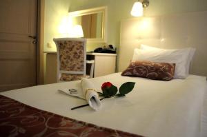 Una cama con una toalla y una rosa. en Avantazh Hotel, en Saratov