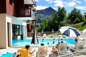 eine Gruppe von Personen, die an einem Pool auf Stühlen sitzen in der Unterkunft Résidence Goélia Les Terrasses du Corbier in Le Corbier