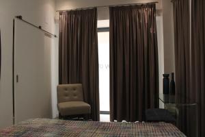 a bedroom with a bed and a chair and a window at Day Off Suite&Hostel in Setúbal