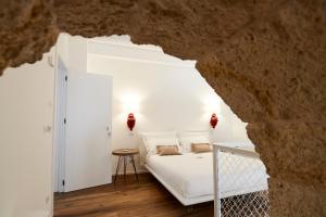 コンヴェルサーノにあるIulius Suite & Spaの洞窟内の白いベッド付きのベッドルーム1室
