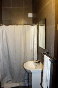a bathroom with a white shower curtain and a sink at Casa Maria Victoria in Beja