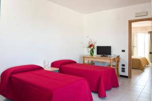 a room with two red beds and a desk with a computer at Corvino Resort in Monopoli