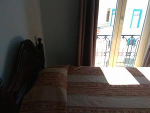 a bed in a room with a window with a blanket at Casa Maria Victoria in Beja