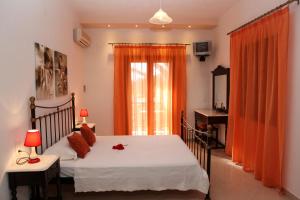 a bedroom with a bed and a window with orange curtains at Maria Studios in Neo Klima
