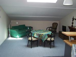 um quarto com uma mesa e cadeiras e um sofá verde em Gite le sorgho em Grisolles