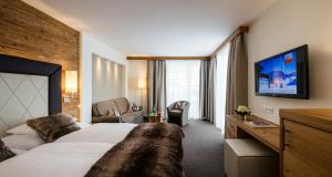 um quarto de hotel com uma cama grande e uma cadeira em Superior Hotel Panorama em Obertauern