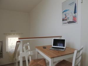 laptopa siedzącego na drewnianym stole z krzesłami w obiekcie Hotel ai Fiori w Grado