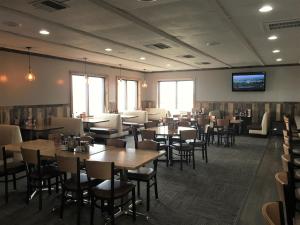 a restaurant with tables and chairs and a flat screen tv at Sunlac Inn Lakota in Lakota