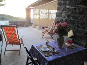 a table with a vase of flowers on a patio at Dammusi La Favarotta in Pantelleria