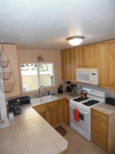 a kitchen with wooden cabinets and a white stove top oven at Kehena Beach Getaway in Kehena