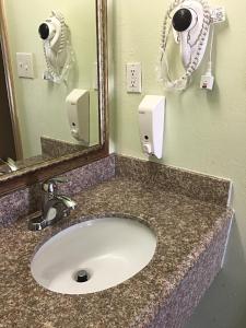 een badkamerbar met een wastafel en een spiegel bij Budget Inn in Hallettsville