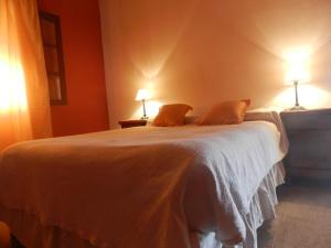 a bedroom with a white bed with two lamps at Los Colorados Hostal in Angastaco