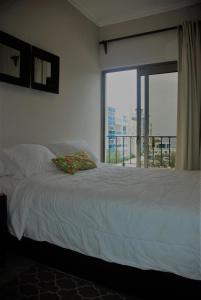 Schlafzimmer mit einem weißen Bett und einem großen Fenster in der Unterkunft E&J Beach Condo in Sosúa