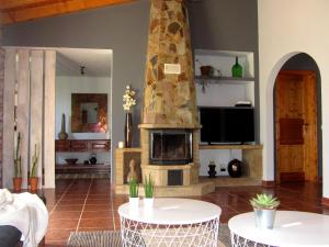 sala de estar con chimenea, 2 mesas y TV en Casa Piteira, en Aljezur