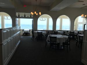 a dining room with tables and chairs and windows at The Three Seasons Resort in Dennis Port