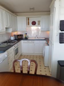 a kitchen with white cabinets and a chair in it at 1 Derby Court Castletown in Castletown