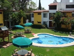 un cortile con piscina con tavoli e ombrelloni di Hotel Vista Hermosa a Cuernavaca
