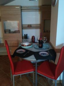 a dining room table with two red chairs and a table with a black and red at Mansardina Sassu in Alghero