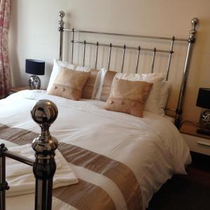 ein Schlafzimmer mit einem großen Bett mit weißer Bettwäsche und Kissen in der Unterkunft Rembrandt Guest House in Great Yarmouth