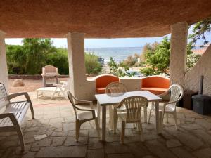 un tavolo e sedie su un patio con vista sull'oceano di Appartamenti In Villa La Marinedda a Isola Rossa