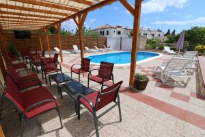a patio with chairs and a swimming pool at Pansion Comfort Sidro in Novalja