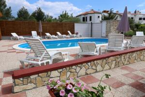 a group of chairs and a swimming pool at Pansion Comfort Sidro in Novalja